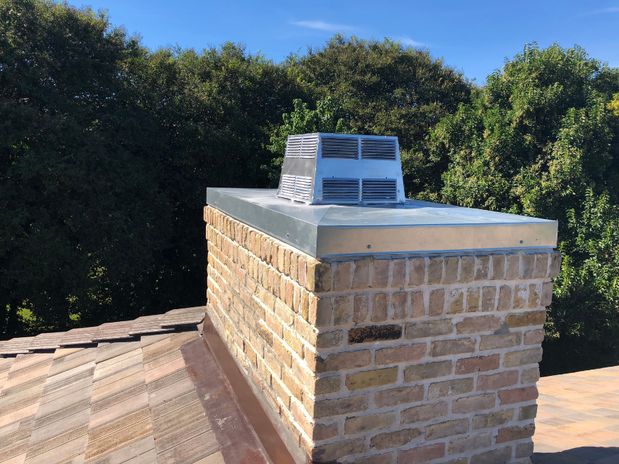 Galvanized cap on light yellow brick chimney